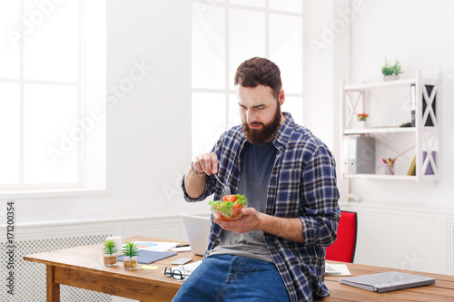 Young businessman has healthy business lunch in modern office interior