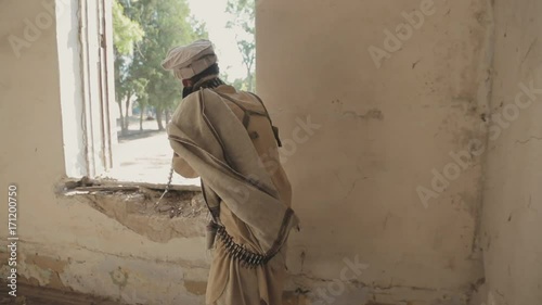 Armed man walking along the abandoned building