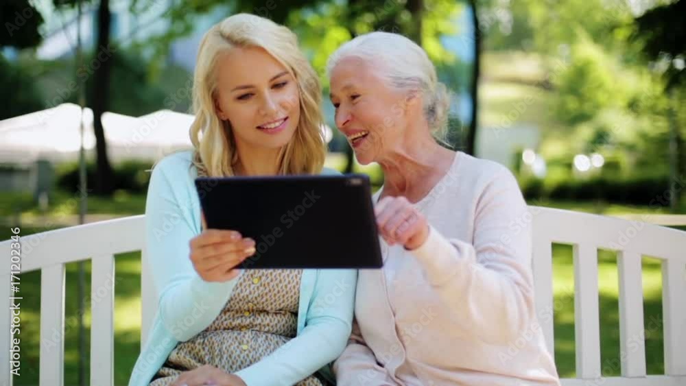 daughter with tablet pc and senior mother at park