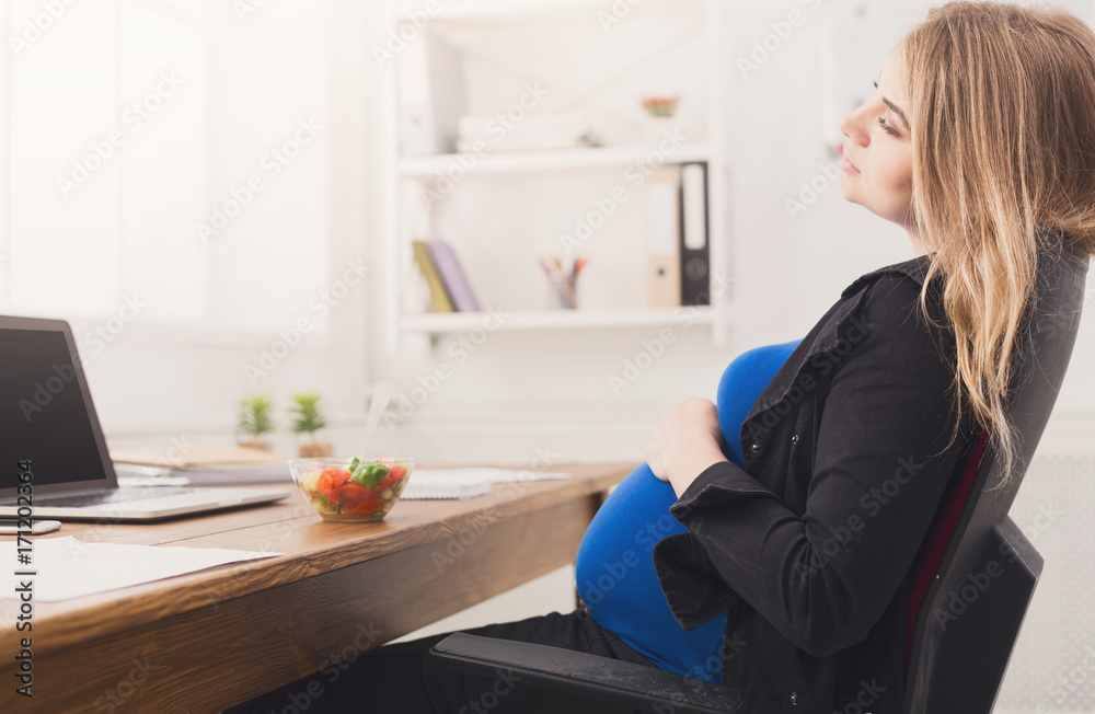 Pregnant businesswoman eating salad at office Pregnant businesswoman eating salad at office