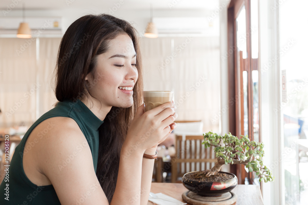 Young happy Asian woman drinking coffee in the coffee shop. Young happy Asian woman drinking coffee in the coffee shop.