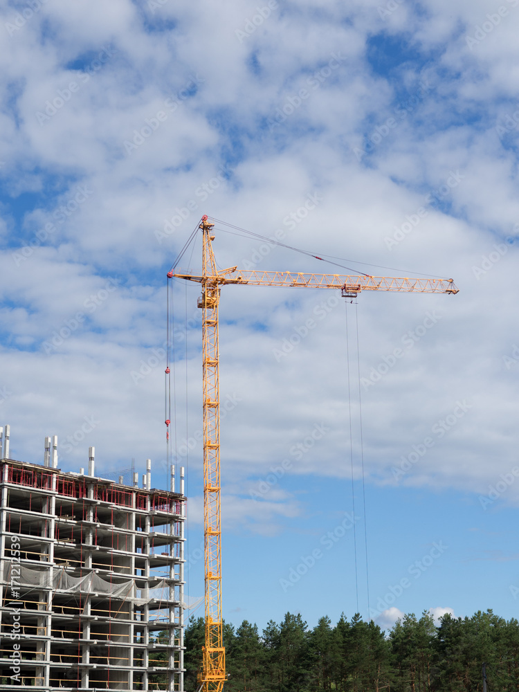 one tap on the background of blue sky at a construction site next to the skeleton of a future high-rise buildings one tap on the background of blue sky at a construction site next to the skeleton of a future high-rise buildings