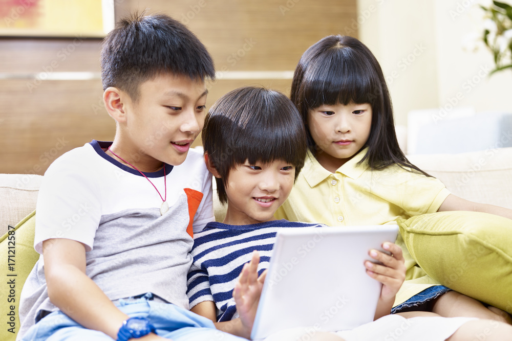 three asian children using digital tablet together three asian children using digital tablet together