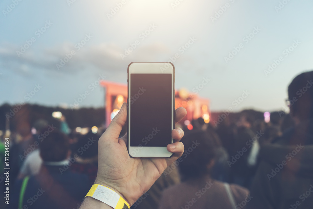 Man holding his white smartphone on a festival