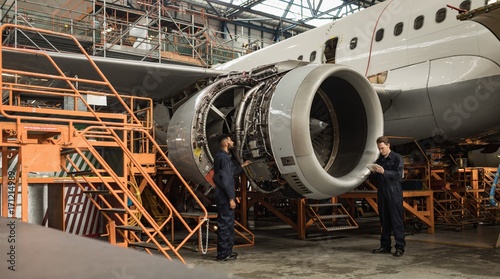 Aircraft maintenance engineers examining turbine engine of