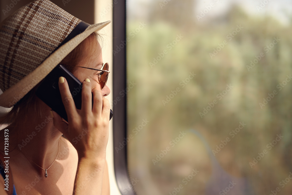Attractive woman calling phone while travelling by train.