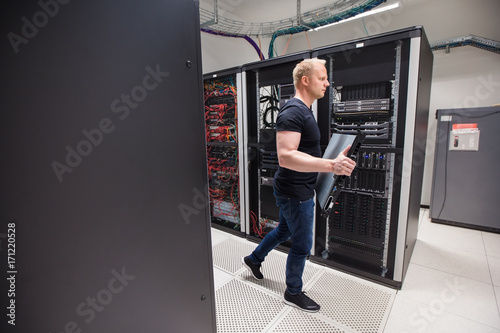 Male Technician Carrying Blade Server While Walking In Datacente