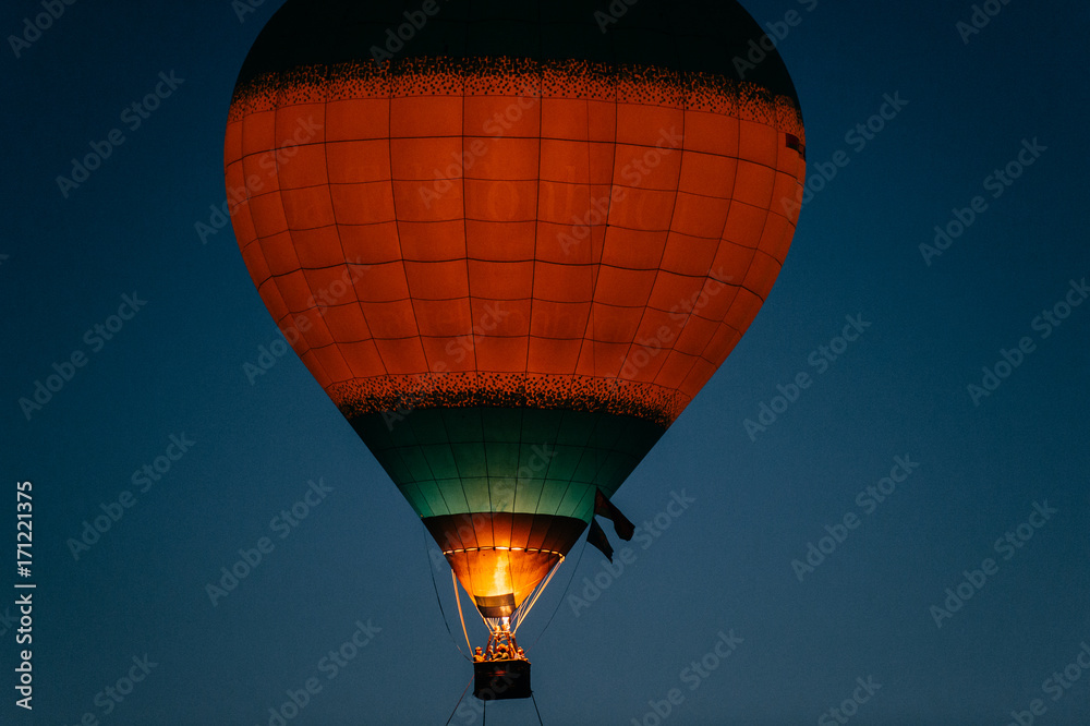 Fototapeta premium Glowing and blinking balloons flight with people high in sky in night. Freedom concept. Romantic recreation. Hot air balls competition. Autumn ballooning festival. Travel and tourism. Airship journey.