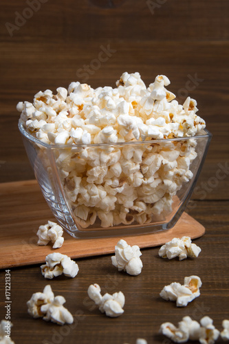 Popcorn in glass bowl on wooden background