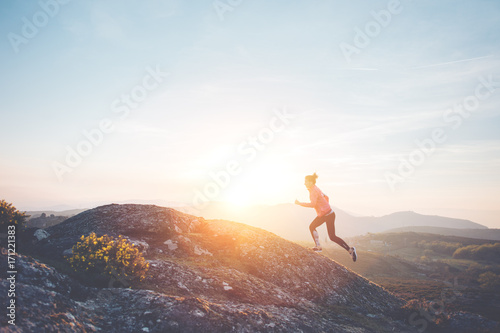 Athletic girl jogging in the mountains enjoying the sunset. Sport tight clothes.  Intentional motion blur. photo