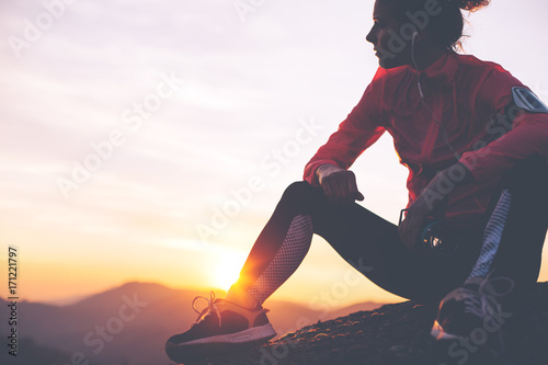 Fototapeta Naklejka Na Ścianę i Meble -  Silhouette of athletic girl resting after a hard training in the mountains at sunset. Sport tight clothes.