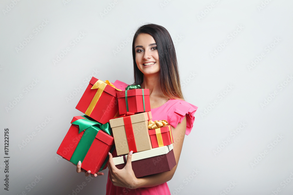 Portrait of beautiful woman holding gift boxes on grey background Portrait of beautiful woman holding gift boxes on grey background