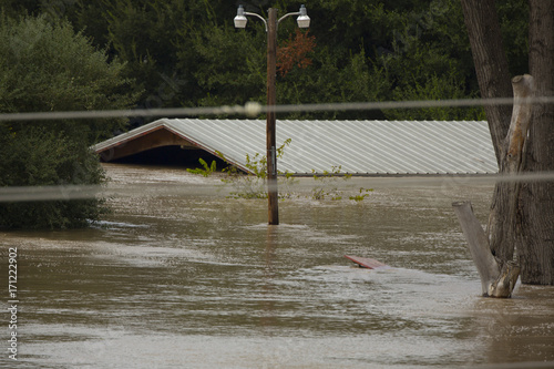 Rooftop, telephone pole and trees protruding from flood waters