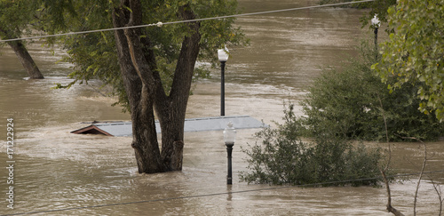 Rooftop and 3 lamp posts sticking through flood water
