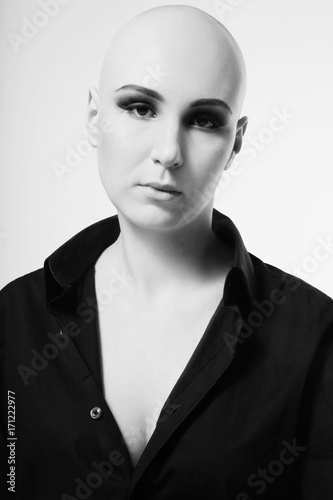 Black and white portrait of young skinhead woman with smoky eyes make-up