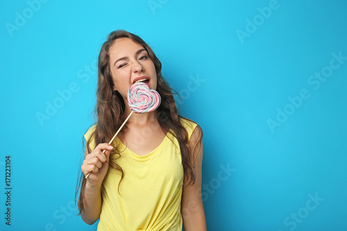 Portrait of young woman with lollipop on blue background
