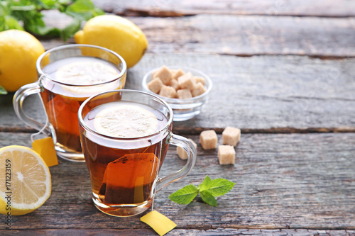 Cup of tea with teabag and lemon on wooden table photo