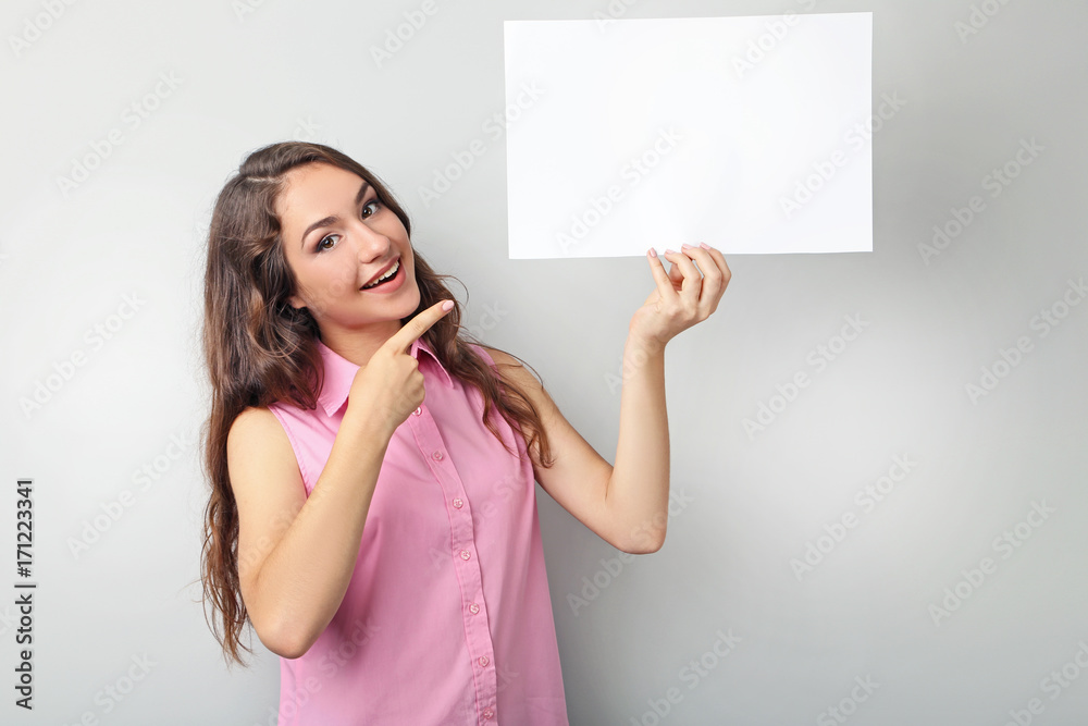 Young woman with blank paper on grey background Young woman with blank paper on grey background