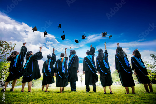 Group of graduates with congratulations throwing graduation hats in the air celebrating. photo