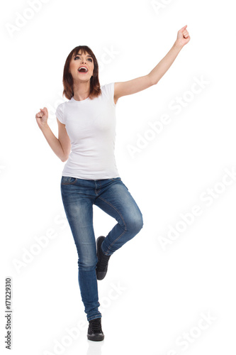 Happy Young Woman Is Standing On One Leg, Gesturing And Shouting