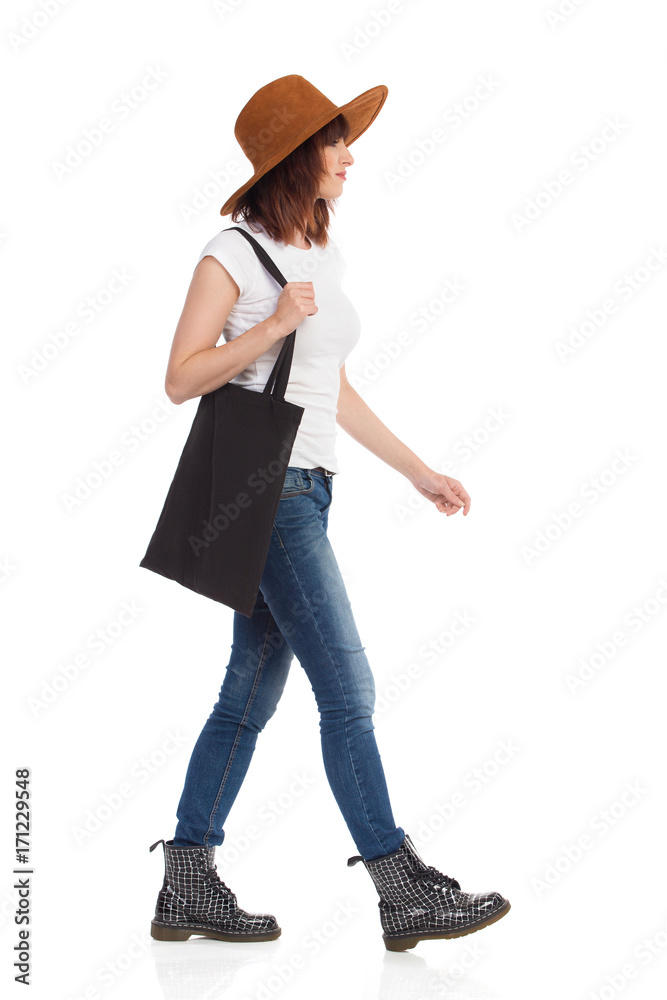 Young Woman In Brown Hat Is Walking With Black Bag On Her Shoulder Young Woman In Brown Hat Is Walking With Black Bag On Her Shoulder