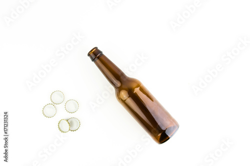 Empty Beer Bottle With Caps Next To It On White Background