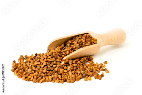 Buckwheat is scattered in a wooden shovel on white background