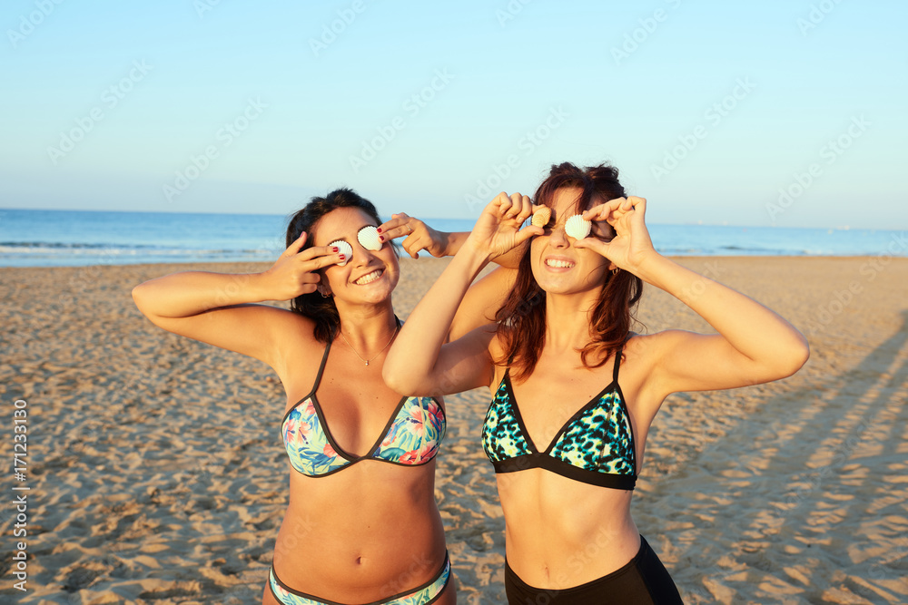 Young friends with seashell in front of eyes
