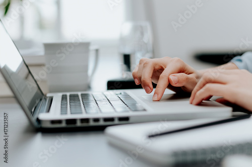 Close up image of woman's hand working on laptop in office.