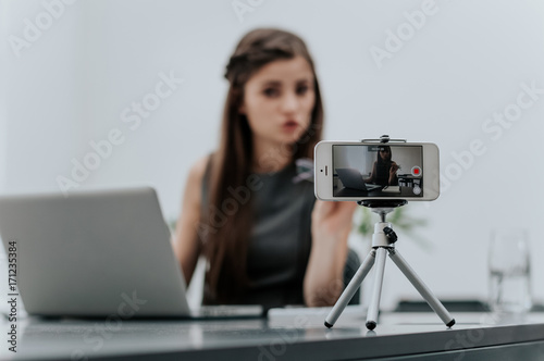 Woman vlogger recording business vlog at office desk photo