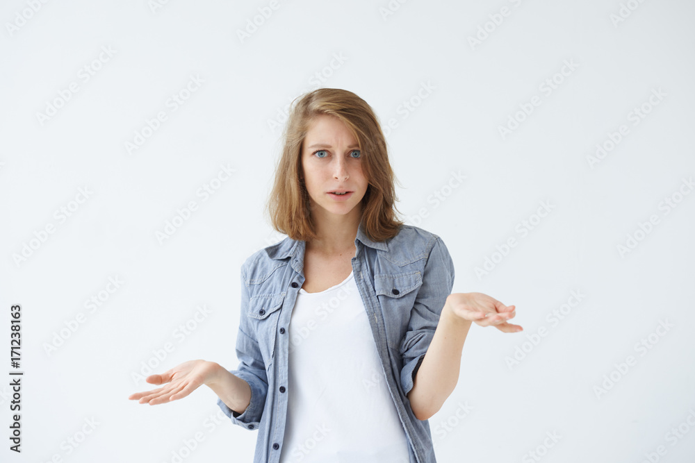 Studio shot of beautiful uncertain confused young female in casual clothes shrugging her shoulders, expressing doubt, uncertainty or indifference as if saying: So what? Who cares? I don't know Studio shot of beautiful uncertain confused young female in casual clothes shrugging her shoulders, expressing doubt, uncertainty or indifference as if saying: So what? Who cares? I don't know