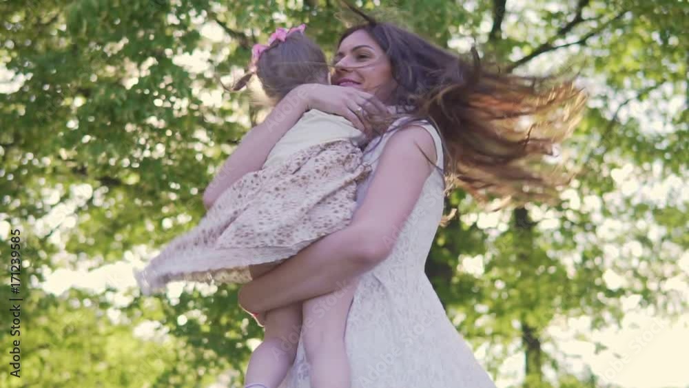 Mom circulates daughter in the park in summer at sunset