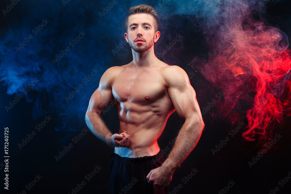 Bodybuilder man with perfect abs, shoulders,biceps, triceps and chest flexing his muscles, studio shoot