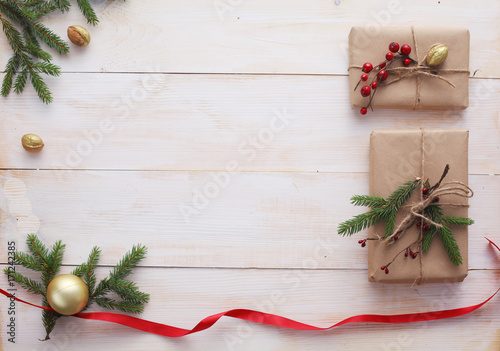 Christmas gift boxes and fir tree branch on wooden table, flat lay