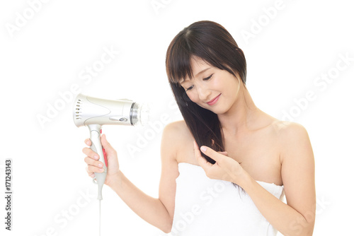 ヘアードライヤーで髪を乾かす女性