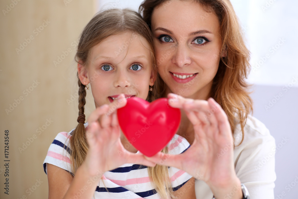 Beautiful smiling woman and kid hold red toy heart Beautiful smiling woman and kid hold red toy heart
