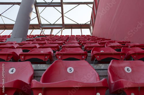 A row of red plastic chairs on a stadium