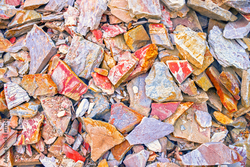 The pattern of the variegated sandstone. A big heap of sandstones, storage space of various natural sandstone. Cracks and colorful layers of sandstone background. Layers of toning colored stones.