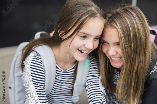 Portrait of two pre teenage girls studying outdoors in school yard