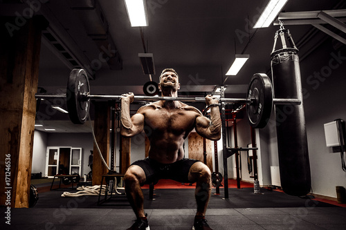 Muscular fitness man doing deadlift a barbell over his head in modern fitness center. Functional training. Snatch exercise