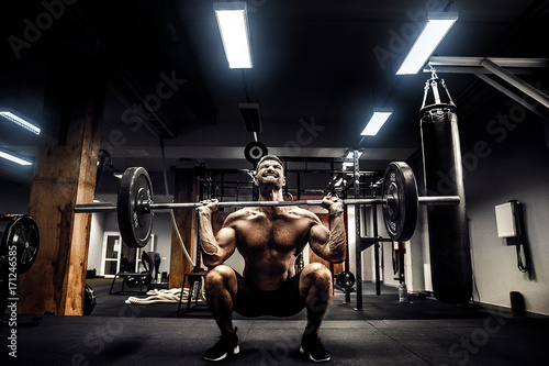 Muscular fitness man doing deadlift a barbell over his head in modern fitness center. Functional training. Snatch exercise photo