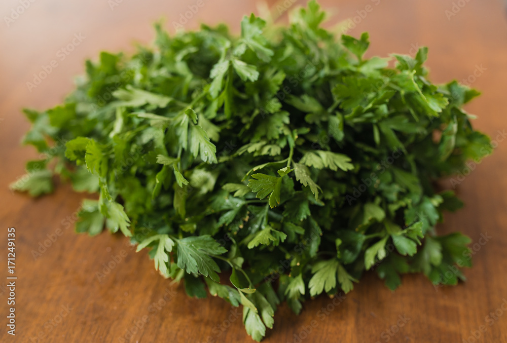 Close up of bunch of fresh garden parsley stems with little imperfections on wooden background