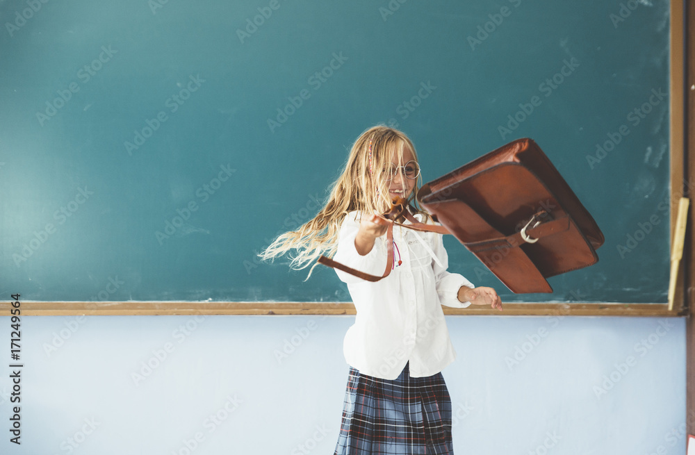 Girl throwing backpack in classroom Stock Photo
