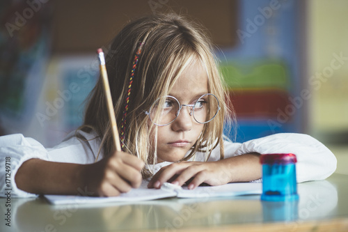 Thoughtful girl writing in class photo