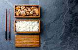 Japanese food. Chicken teriyaki with rice in wooden bento lunch box. slate background, top view.