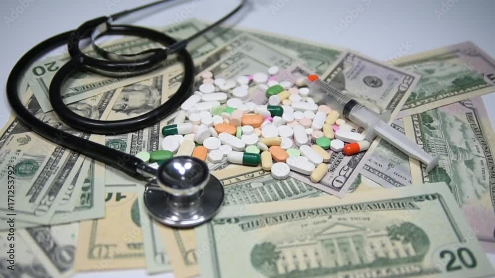 Pills and capsules on dollars, with stethoscope and syringe. Health care costs concept. Slow motion. Pills and capsules on dollars, with stethoscope and syringe. Health care costs concept. Slow motion.