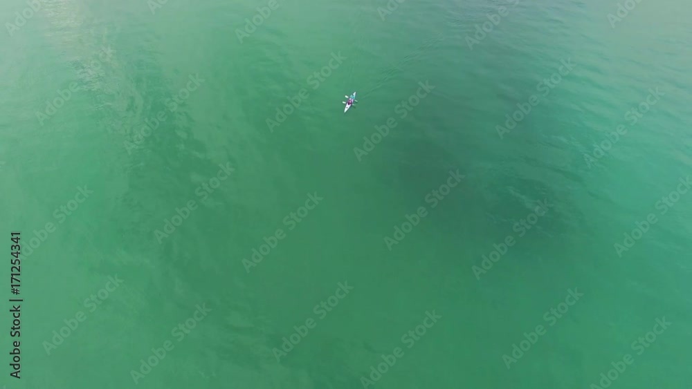 Backward flight over ocean bay water away from a double kayak with camera tilt Backward flight over ocean bay water away from a double kayak with camera tilt