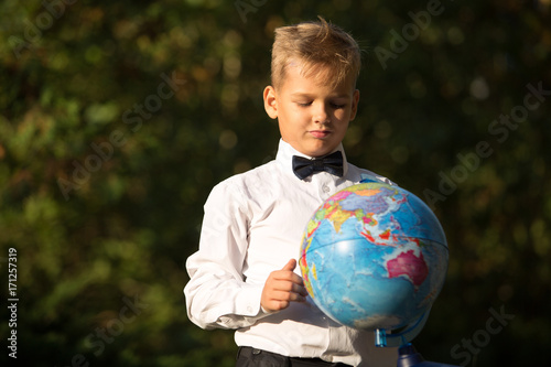 Portrait of a boy, a schoolboy with a globe in his hands in the garden. Portrait, childhood, education.