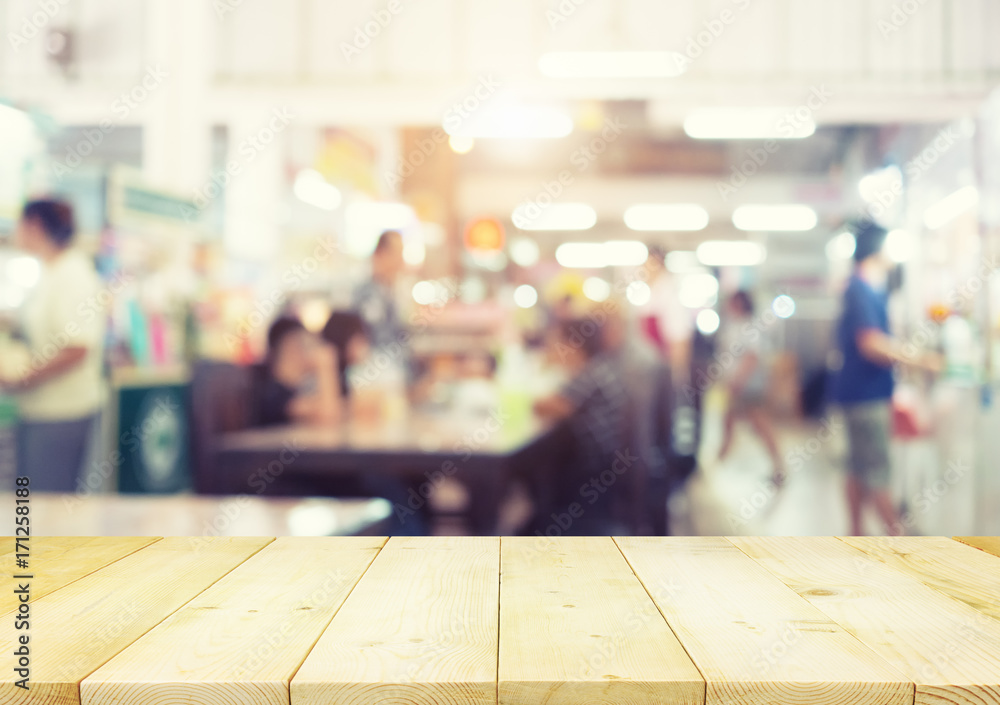 Defocused or blurred photo of food court montage with wood table top use for background.