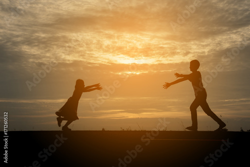 young happy boy and his little cute sister walking on the sea shore on a warm summer evening. Friendship between siblings. relationship between brother and sister. Family concepts.
